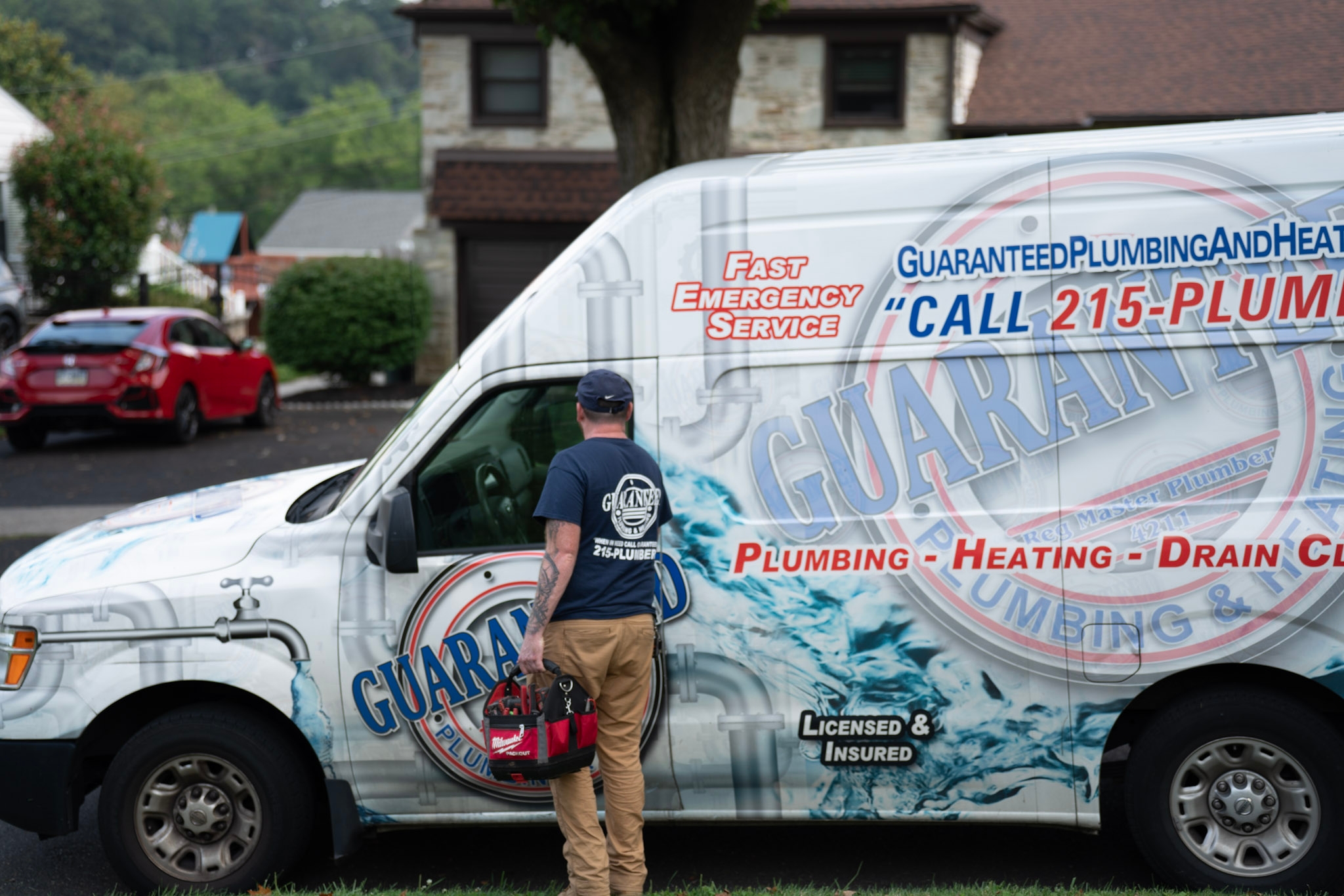 a workger pulling tools out of a Guaranteed Plumbing van