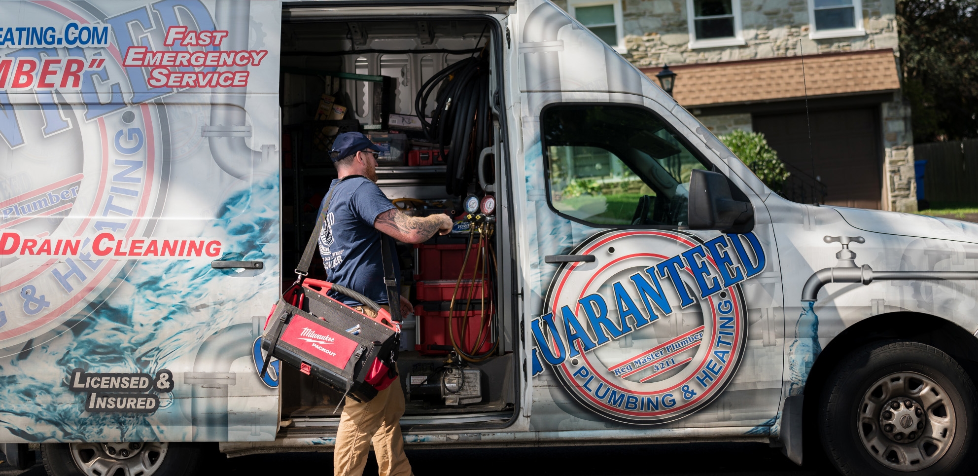 a workger pulling tools out of a Guaranteed Plumbing van